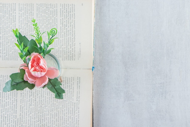 Fleurs gracieuses dans un pot sur le livre, sur le tableau blanc.