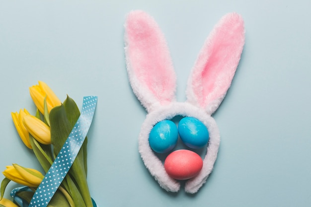 Photo gratuite fleurs près des oreilles de lapin et des oeufs