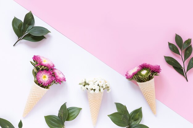 Fleurs roses et blanches dans un cornet de crème glacée à la gaufre sur une double surface