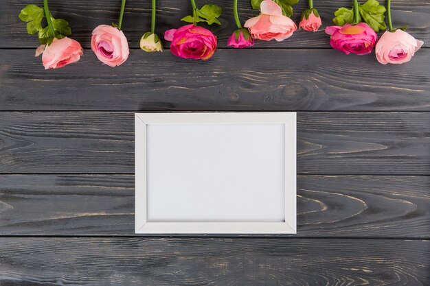 Fleurs roses avec cadre vide sur table en bois