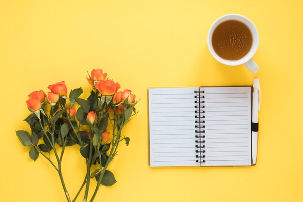 Fleurs roses avec carnet et thé sur la table