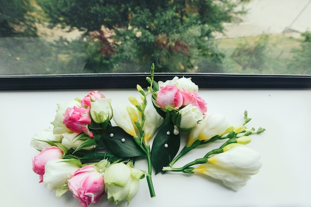 Les fleurs roses décorées de perles reposent sur le rebord de la fenêtre