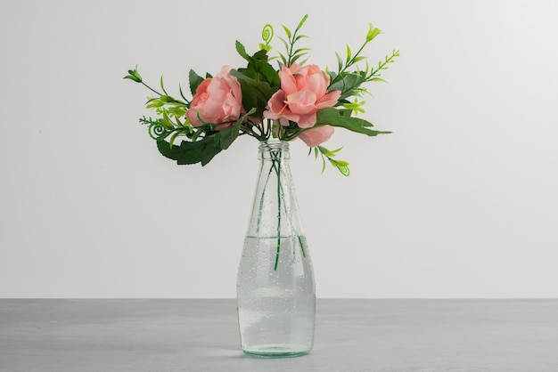 Fleurs roses avec des feuilles vertes dans un vase en verre