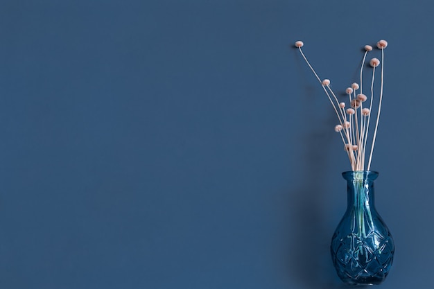 Photo gratuite fleurs séchées et un vase sur un mur bleu.