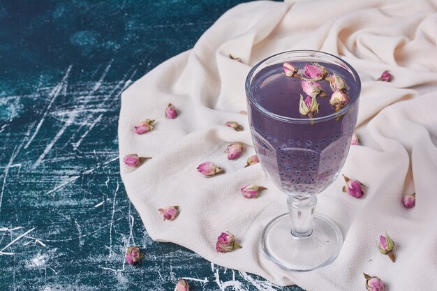 Fleurs avec une tasse de boisson sur bleu.