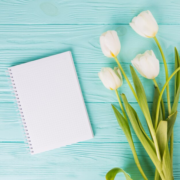 Fleurs de tulipes avec cahier vierge sur une table en bois