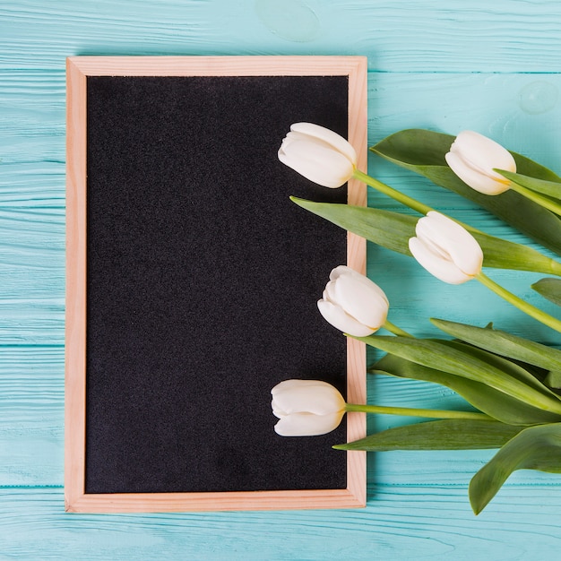 Photo gratuite fleurs de tulipes avec tableau blanc sur table