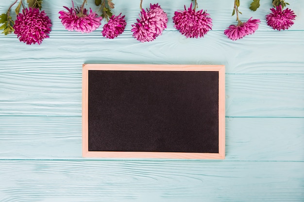 Photo gratuite fleurs violettes avec tableau blanc sur une table en bois bleue