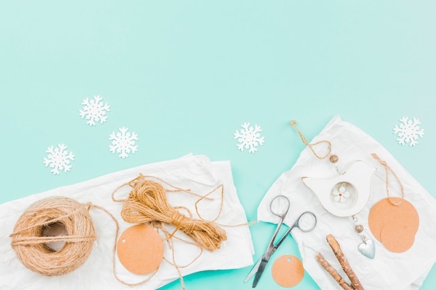 Photo gratuite flocon de neige en papier blanc; fil de jute; papier; ciseaux et bâton pour faire de la pièce suspendue spectacle sur fond turquoise