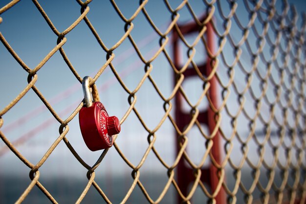 Flou d'un cadenas rouge suspendu à une clôture en treillis métallique