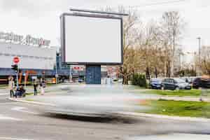 Photo gratuite flou de véhicule en passant par le panneau d'affichage vide sur la route