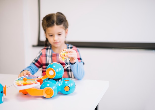 Floue petite fille tenant des câbles à la main en regardant jouets électriques