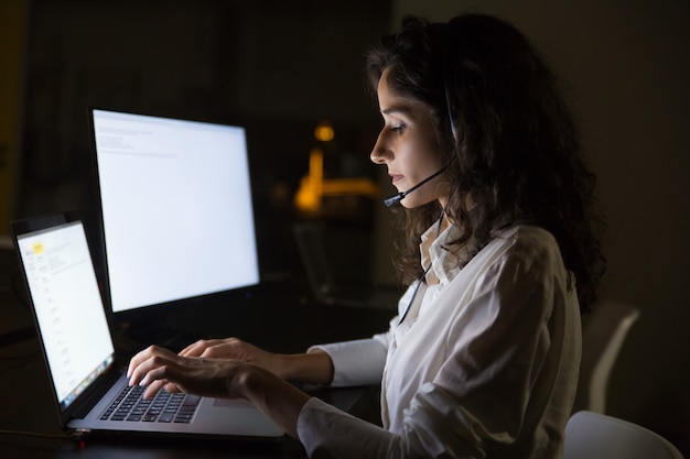 Focused businesswoman in headset using laptop