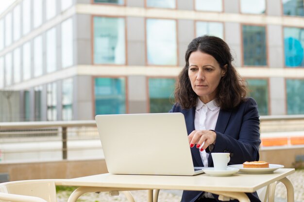 Focused businesswoman using laptop in outdoor cafe