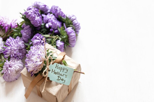 Fond festif de la fête des mères avec boîte-cadeau et fleurs de chrysanthème fraîches sur fond blanc, espace de copie.