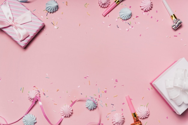 Fond de fête rose avec des bonbons; ventilateurs de fête et ruban frisé