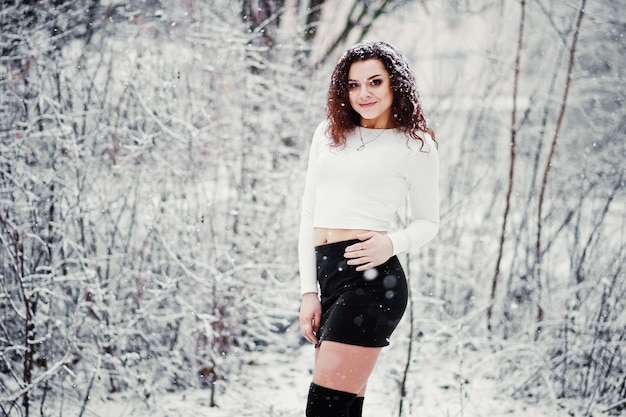 Fond de fille brune bouclée chute de neige porter sur une mini jupe noire et des bas de laine Modèle en hiver Portrait de mode par temps neigeux Instagram photo tonique