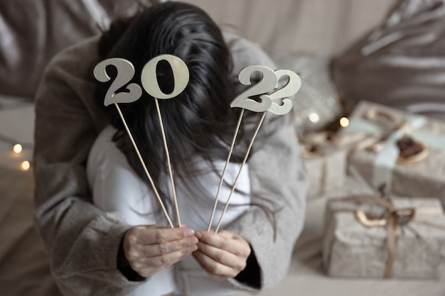 Fond de Noël avec des numéros en bois 2022 sur des bâtons dans des mains féminines