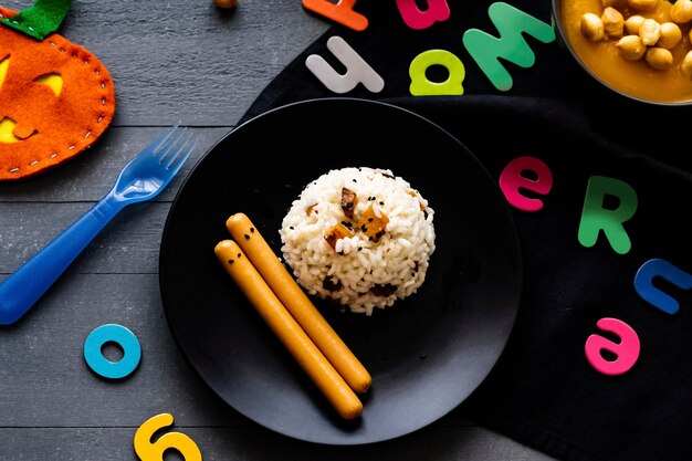 Fond de nourriture de fête d'Halloween d'enfants avec le risotto de potiron et les saucisses de Francfort