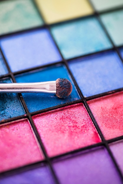 Photo gratuite fond de palette d'ombre à paupières colorée avec pinceau de maquillage