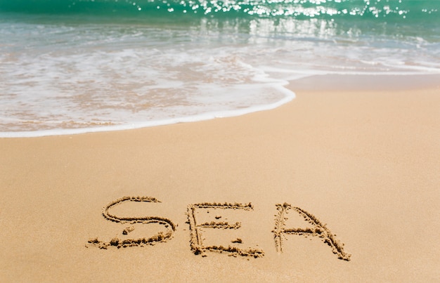 Fond de plage avec mot mer écrit dans le sable