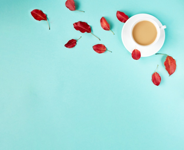 Fond plat d'automne sur bleu. composition avec des feuilles rouges réalistes et une tasse de café. bonjour concept d'octobre. espace de copie