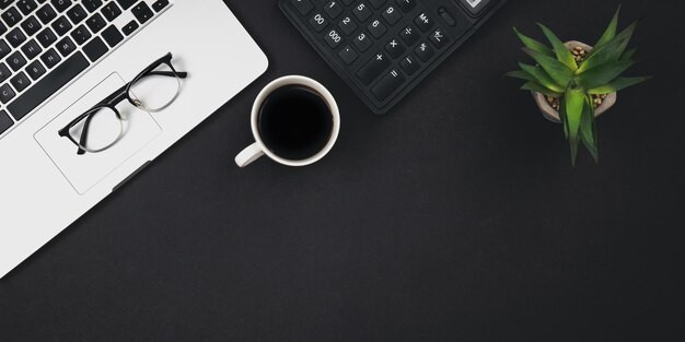 Fond plat noir avec tasse à café pour ordinateur portable et vue de dessus de la calculatrice