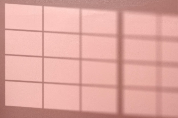 Fond rose avec ombre de fenêtre reflétée sur le mur