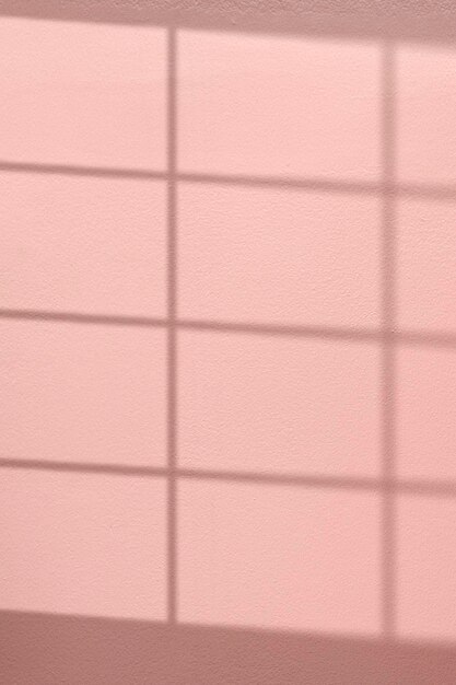 Fond rose avec ombre de fenêtre reflétée sur le mur