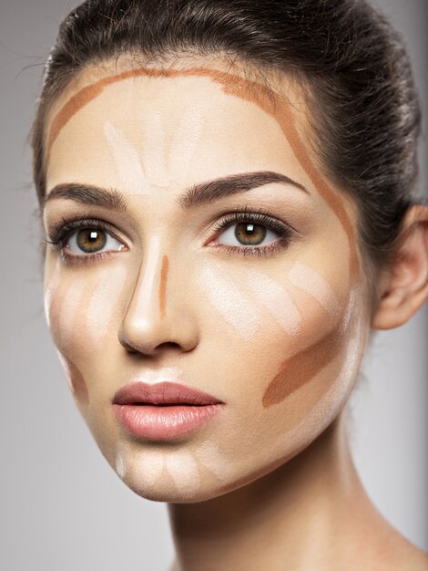 Le fond de teint de maquillage cosmétique est sur le visage de la femme. Concept de traitement de beauté. La fille fait du maquillage.