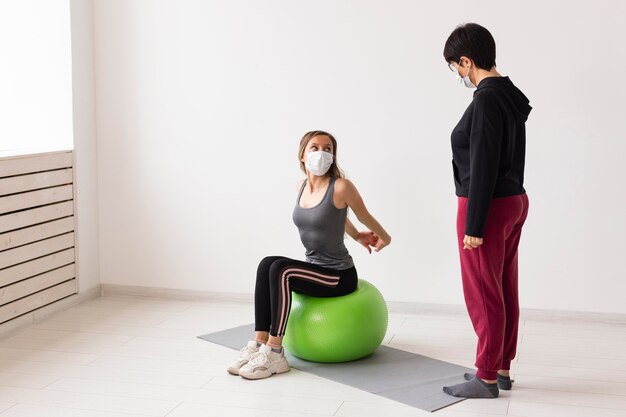 Formateur montrant à la femme comment utiliser un ballon de fitness