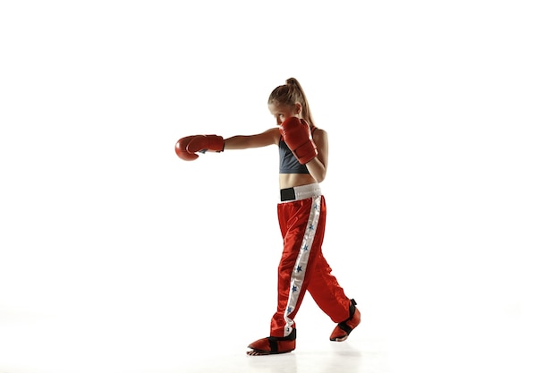 Formation de combattant de kickboxing jeune femme isolée sur mur blanc. fille blonde caucasienne en tenue de sport rouge pratiquant les arts martiaux. concept de sport, mode de vie sain, mouvement, action, jeunesse.
