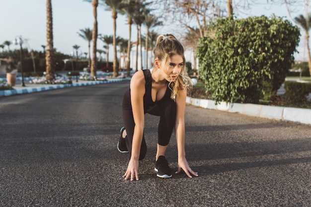 Formation dans la matinée ensoleillée d'une belle femme joyeuse se préparant à courir dans la rue. Été, sportive forte, énergie, motivation, mode de vie sain, entraînement, bonheur