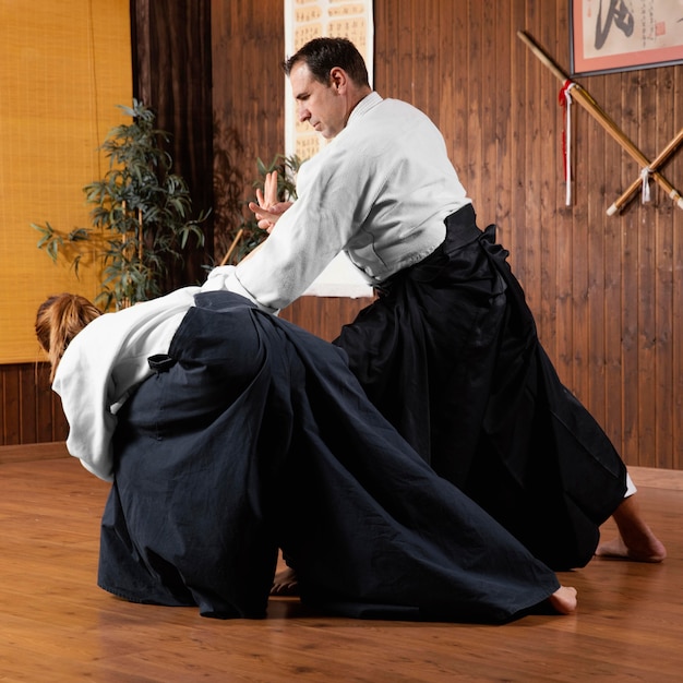 Formation d'instructeur d'arts martiaux masculin dans la salle de pratique avec stagiaire