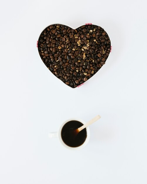 En forme de coeur avec des grains de café et une tasse à café