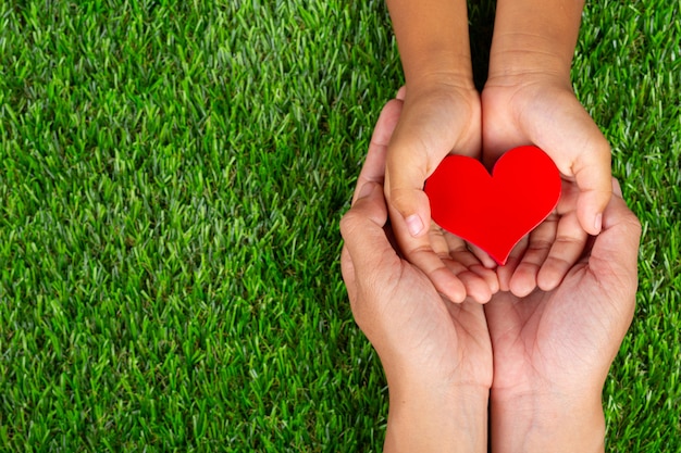 Forme de coeur rouge dans les mains des membres de la famille tenant