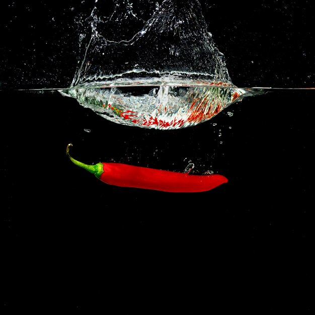 Forme d&#39;éclaboussure de couronne d&#39;eau par le piment rouge tombant dans l&#39;eau