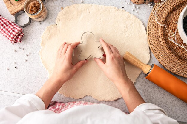 Photo gratuite forme pour les biscuits de noël dans les mains des femmes sur le fond de la pâte