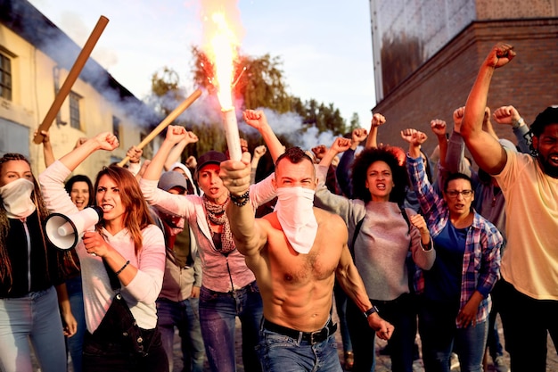 Foule furieuse de personnes protestant avec une torche enflammée dans les rues de la ville