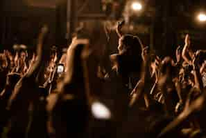 Photo gratuite foule de gens aux bras levés s'amusant au festival de musique de nuit