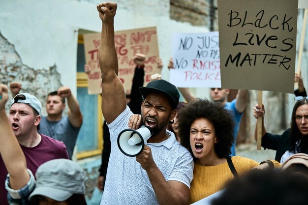 Foule multiethnique de personnes luttant pour la liberté lors d'une manifestation contre la discrimination raciale L'accent est mis sur un couple afro-américain criant à travers un mégaphone