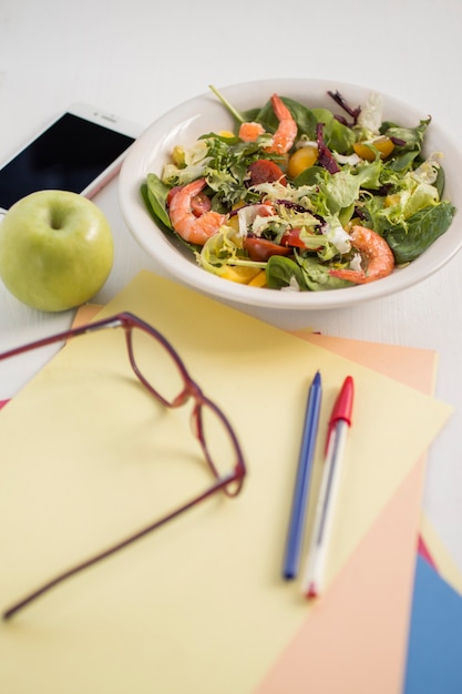 Photo gratuite fournitures de bureau et bol de salade