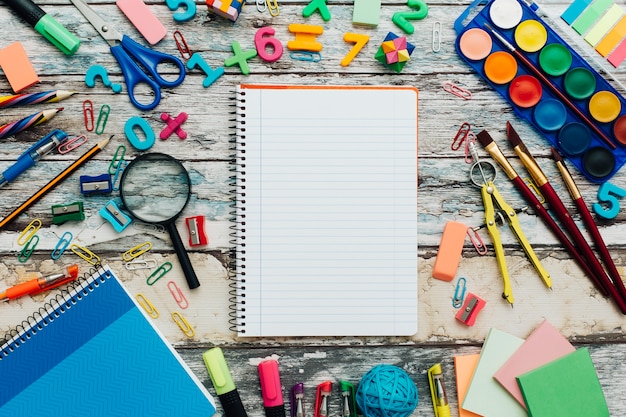 Fournitures scolaires et cahier sur fond de bois.