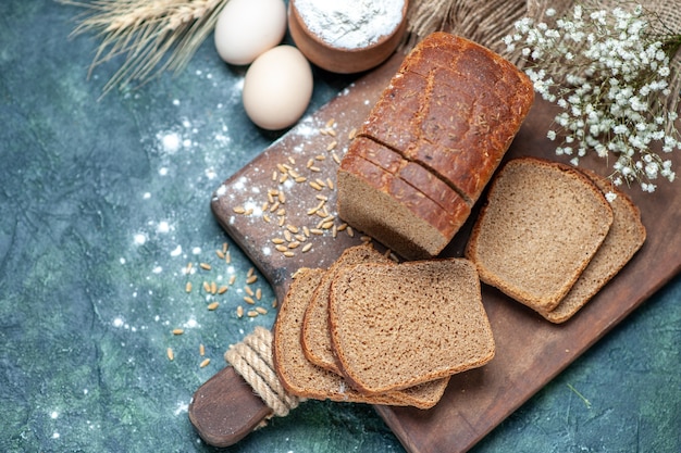 Frais généraux des blés de pain noir diététiques sur des pointes de planche de bois farine d'oeufs de fleur dans un bol sur fond bleu