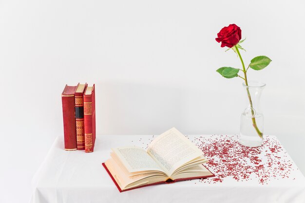 Frais rose rouge dans un vase près de livre ouvert sur la table