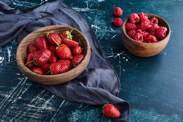 Fraise et framboises dans une tasse en bois.