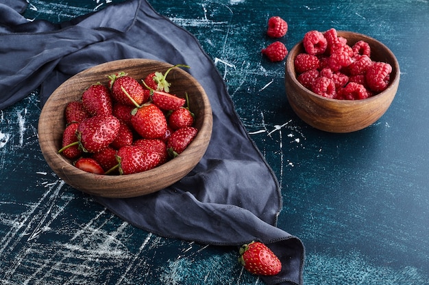 Fraise et framboises dans une tasse en bois.