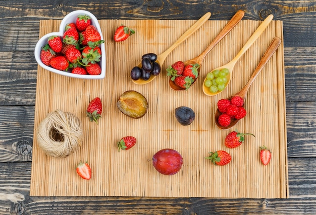 Fraises dans un bol avec des fruits sur une cuillère en bois