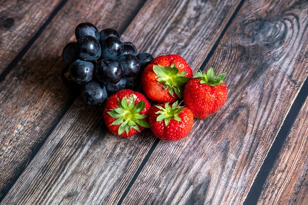 Fraises écossaises fraîches et raisins noirs sur le dessus de la table en bois.