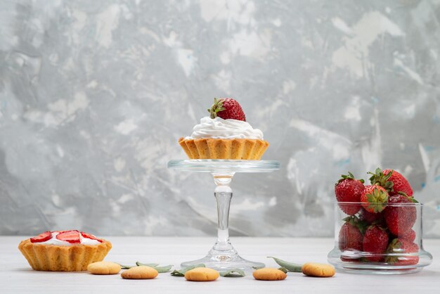 Fraises rouges fraîches moelleuses et délicieuses baies avec des gâteaux et des biscuits sur un bureau léger